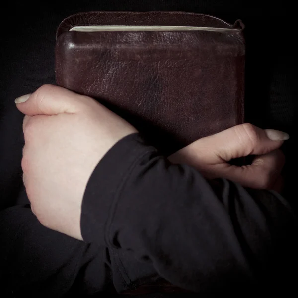 Kvinnor innehar en bibel till hennes bröst — Stockfoto