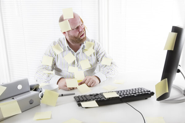 Офисный работник с блокнотами повсюду
