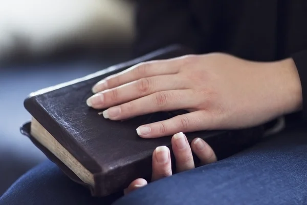 Doblar las manos sobre una Biblia — Stockfoto