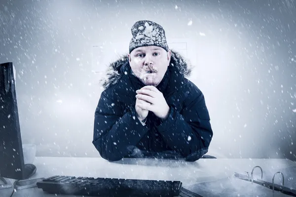 Zakenman in een koude kantoor met sneeuw en ijs Stockfoto