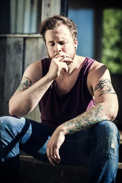 Depressed man sits on staircase and smokes — Stock Photo, Image