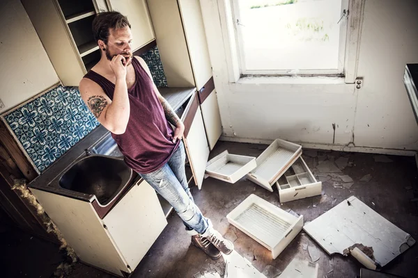 Man smokes cigarettes in messy kitchen — Stock Photo, Image