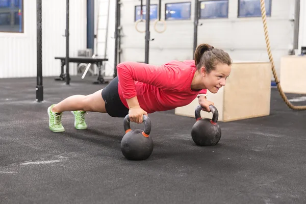 Νεαρή γυναίκα εκπαιδεύει pushups με kettlebells — Φωτογραφία Αρχείου