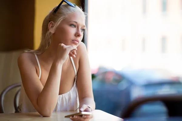 Thinking young woman looking out the window — Stock Photo, Image