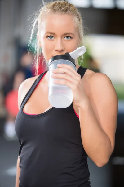 Blonde girl drinks water at fitness gym center — Stock Photo, Image