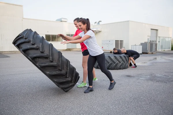 Grupo de personas volteando neumáticos pesados como entrenamiento — Foto de Stock