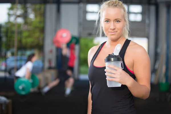 Vrouw rust en drinkwater op fitness gym — Stockfoto