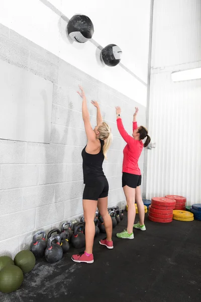 Two women throws medicine balls in fitness gym — Stock Photo, Image