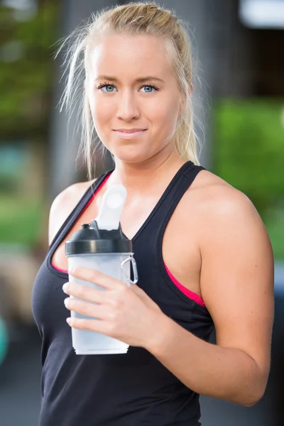 Aantrekkelijke blonde vrouw drinkwater op fitness gym — Stockfoto