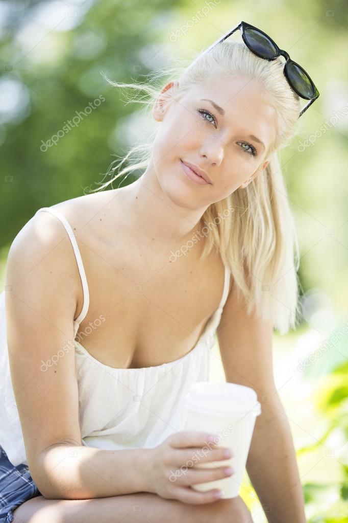 Attractive young girl drinking coffee in park