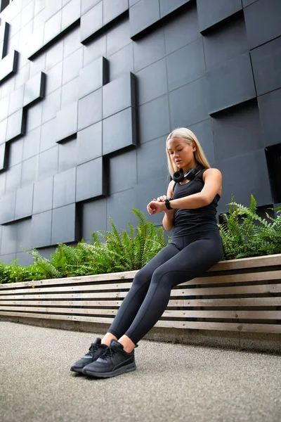 Corredor femenino comprueba el rendimiento del entrenamiento en el reloj inteligente — Foto de Stock