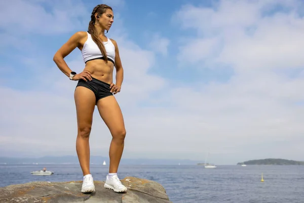 Fit Frau in Sportbekleidung schaut weg, während sie auf dem Felsen steht — Stockfoto