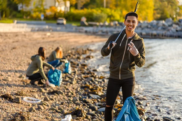 Pyšný muž čistí oceán s dobrovolníky za slunečného dne — Stock fotografie