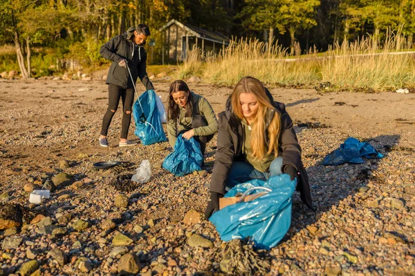 Grupo de voluntarios recogiendo basura plástica en la playa y en el mar — Foto de Stock