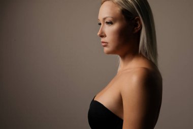 Kahverengi arka planda sarı saçlı, muhteşem, doğal bir kadının karanlık stüdyo portresi.