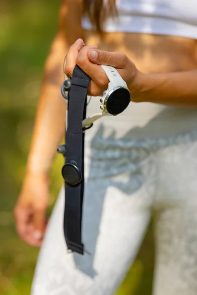 Primer plano de la mujer que usa el dispositivo de reloj inteligente fitness y el monitor de frecuencia cardíaca de la correa del pecho bajo entrenamiento —  Fotos de Stock