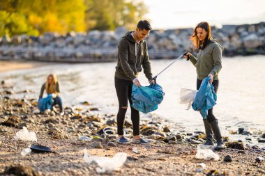 Güneşli bir günde plajı temizleyen bir grup gönüllü.