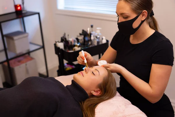 Kosmetikerin behandelt weibliche Klientin für Wimpernverlängerung — Stockfoto