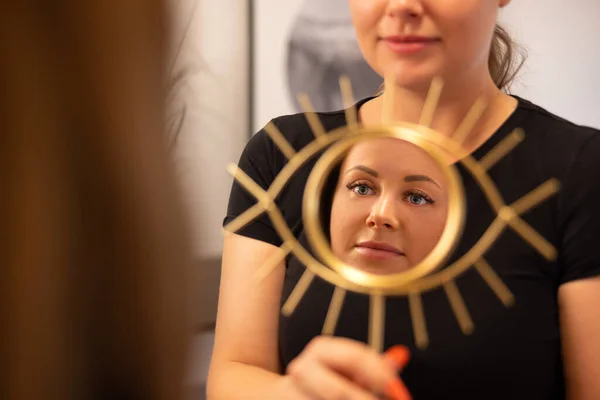 Glimlachende schoonheidsspecialiste houden spiegel voor vrouwelijke klant — Stockfoto