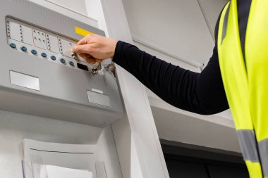 Close-up of midsection of electrician opening fire panel in server room at datacenter