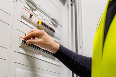 Close-up of midsection of male technician checking electric fuse board in server room at datacenter