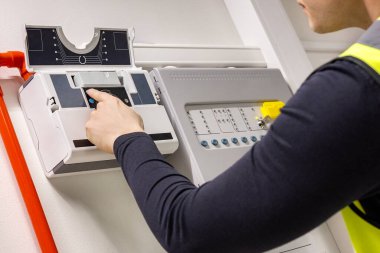 Close-up of midsection of male technician checking smoke detector in server room at datacenter