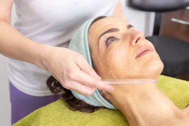 Plastik bir aletle hastaya lazer tüy aldırmak için anestezi kremleri uyguluyorum.