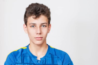 Gri arka planda koyu renk saçlı mavi tişörtlü bir çocuğun portresi. Ciddi ama nazik bir bakışı var. Uzayı kopyala İzole edilmiş