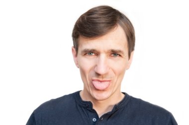 A man on a white background smiles and shows humorously the tongue. Horizontal. Isolated. Copy space