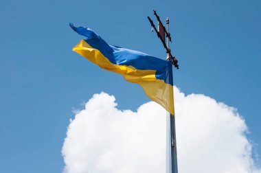 Ukrainian national flag yellow-and-blue develops against a background of blue sky with clouds. Ukraine is a happy country. Copy space