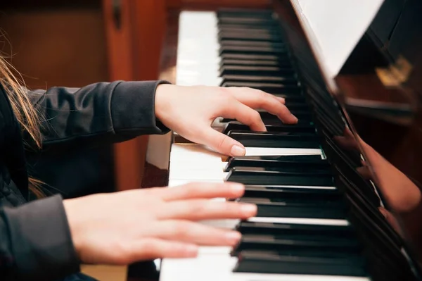 Concept of playing piano lessons. The young girl plays at home on a piano and studies new musical works. Close up