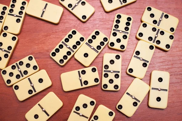 A domino game board is lying on a wooden table chaosfully scattered after the game