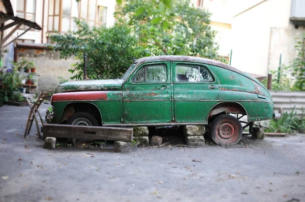Very old Soviet car which no longer goes because the broken is standing in the middle of the street in the city. Horizontal