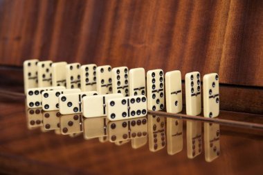 The elements of the board game domino are lying, standing arranged on a wooden background. An interesting board game dominoes for the whole family