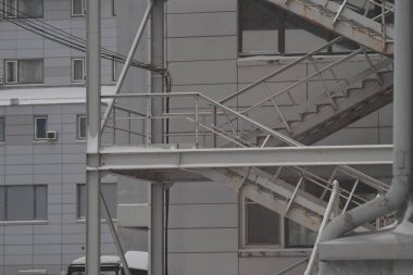 Tam renkli yatay fotoğraf. İnşaat malzemelerinin dış unsurları: Merdivenler, korkuluklar. Karlı hava, kar fırtınası, buz.