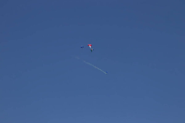 A military paratrooper launched from a helicopter unrolls the Italian flag, in a day of the Italian republic.