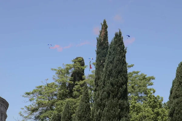 İtalyan cumhuriyetinin bir gününde, bir helikopterden havalanan askeri paraşütçü İtalyan bayrağını açıyor..