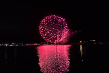 Bacoli, Napoli, 9 Ağustos 2022. Havai fişekler gökyüzünü çeşitli renklerle boyuyor ve Miseno Gölü 'ne yansıtılarak nefes kesici bir manzara yaratıyor..