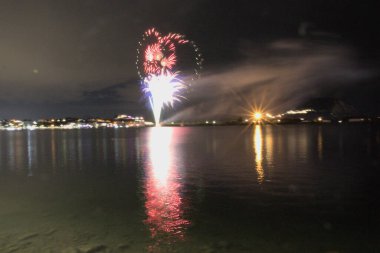 Bacoli, Napoli, 9 Ağustos 2022. Havai fişekler gökyüzünü çeşitli renklerle boyuyor ve Miseno Gölü 'ne yansıtılarak nefes kesici bir manzara yaratıyor..