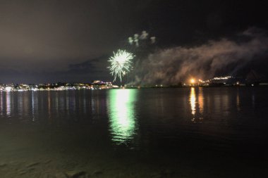 Bacoli, Napoli, 9 Ağustos 2022. Havai fişekler gökyüzünü çeşitli renklerle boyuyor ve Miseno Gölü 'ne yansıtılarak nefes kesici bir manzara yaratıyor..