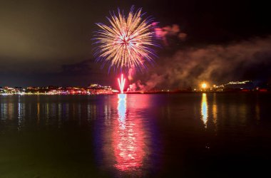 Bacoli, Napoli, 9 Ağustos 2022. Havai fişekler gökyüzünü çeşitli renklerle boyuyor ve Miseno Gölü 'ne yansıtılarak nefes kesici bir manzara yaratıyor..
