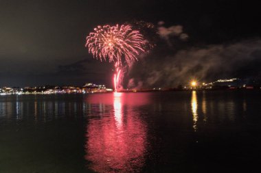 Bacoli, Napoli, 9 Ağustos 2022. Havai fişekler gökyüzünü çeşitli renklerle boyuyor ve Miseno Gölü 'ne yansıtılarak nefes kesici bir manzara yaratıyor..