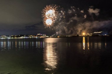 Bacoli, Napoli, 9 Ağustos 2022. Havai fişekler gökyüzünü çeşitli renklerle boyuyor ve Miseno Gölü 'ne yansıtılarak nefes kesici bir manzara yaratıyor..