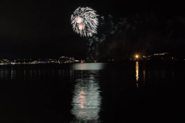 Bacoli, Napoli, 9 Ağustos 2022. Havai fişekler gökyüzünü çeşitli renklerle boyuyor ve Miseno Gölü 'ne yansıtılarak nefes kesici bir manzara yaratıyor..