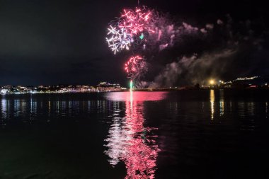 Bacoli, Napoli, 9 Ağustos 2022. Havai fişekler gökyüzünü çeşitli renklerle boyuyor ve Miseno Gölü 'ne yansıtılarak nefes kesici bir manzara yaratıyor..