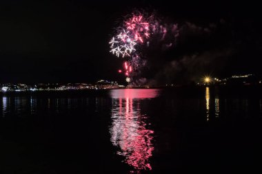 Bacoli, Napoli, 9 Ağustos 2022. Havai fişekler gökyüzünü çeşitli renklerle boyuyor ve Miseno Gölü 'ne yansıtılarak nefes kesici bir manzara yaratıyor..