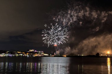 Bacoli, Napoli, 9 Ağustos 2022. Havai fişekler gökyüzünü çeşitli renklerle boyuyor ve Miseno Gölü 'ne yansıtılarak nefes kesici bir manzara yaratıyor..