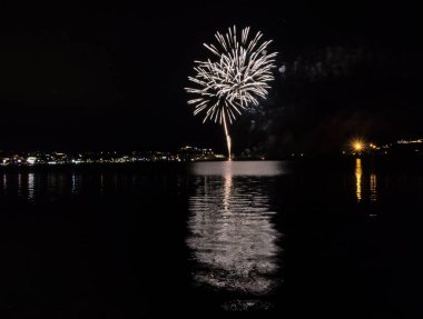 Bacoli, Napoli, 9 Ağustos 2022. Havai fişekler gökyüzünü çeşitli renklerle boyuyor ve Miseno Gölü 'ne yansıtılarak nefes kesici bir manzara yaratıyor..