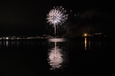 Bacoli, Napoli, 9 Ağustos 2022. Havai fişekler gökyüzünü çeşitli renklerle boyuyor ve Miseno Gölü 'ne yansıtılarak nefes kesici bir manzara yaratıyor..