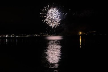 Bacoli, Napoli, 9 Ağustos 2022. Havai fişekler gökyüzünü çeşitli renklerle boyuyor ve Miseno Gölü 'ne yansıtılarak nefes kesici bir manzara yaratıyor..